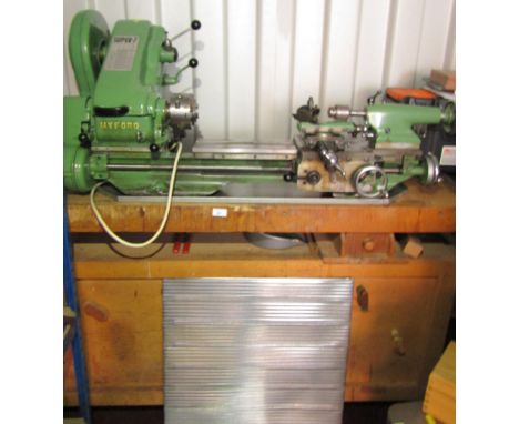A Myford Super 7 metal turning lathe, upon a beech workbench, with cabinet base and record bench vice.