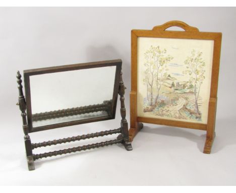 An Edwardian oak swing frame toilet mirror, 53cm x 60.5cm, and a mahogany framed silk fire screen stitched with a village lan