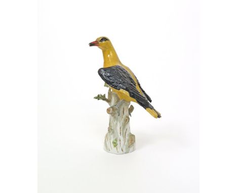 A Meissen model of a Golden Oriole, 19th century, perched on a tall tree stump with head turned to sinister, its wings slight