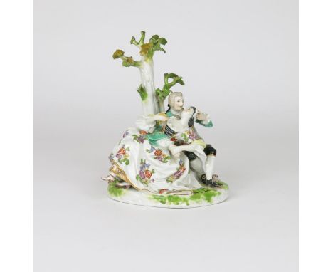 A Meissen-style crinoline figure group of lovers, c.1770, after the model by J J Kändler, the amorous pair seated beneath a t