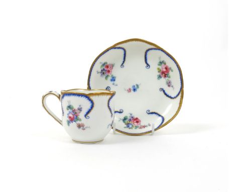 A Sèvres-style coffee cup and saucer, 18th century, painted with flowers within moulded feuille de choux borders picked out i