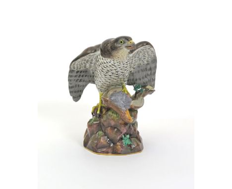 A large Meissen model of a hawk with its prey, 19th century, the predator perched on top of a rocky stump with a dead bird be