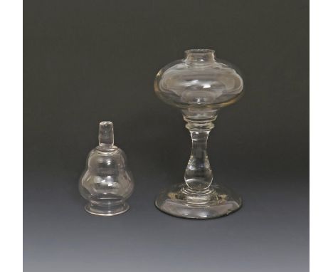 A glass oil lamp, early 19th century, with flattened globular reservoir raised on a baluster stem above a heavy domed foot, a