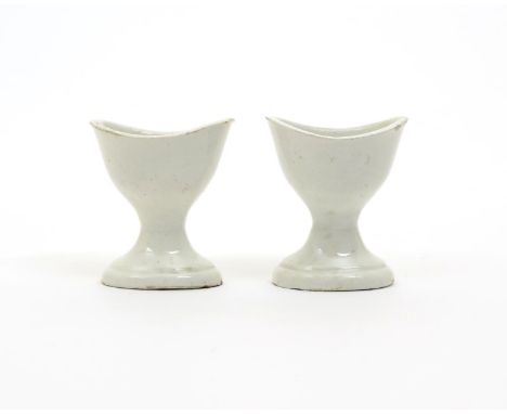 A pair of creamware eyebaths, 1st half 19th century, the deep U-shaped bowls finely potted and raised on flared oval feet wit