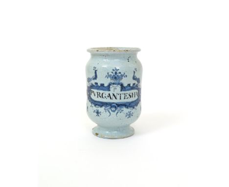 A small Continental tin-glazed drug jar or albarello, 18th century, painted in blue with a wide cartouche topped by two peaco