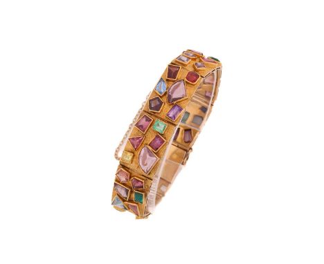 A Modernist coloured gem-set bracelet, comprises eight hinged textured gold panels, each panel has six different collet-set g