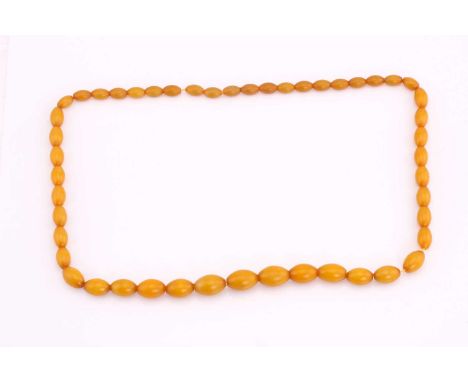 A butterscotch coloured amber bead necklace, strung with barrel-shaped opaque beads, approximately measuring 93 cm, total wei