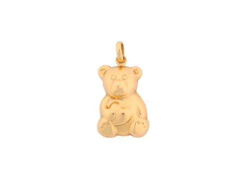 A yellow metal teddy bear pendant, comprises a repoussé of a smiling teddy bear holding a heart with its paw, attached with a