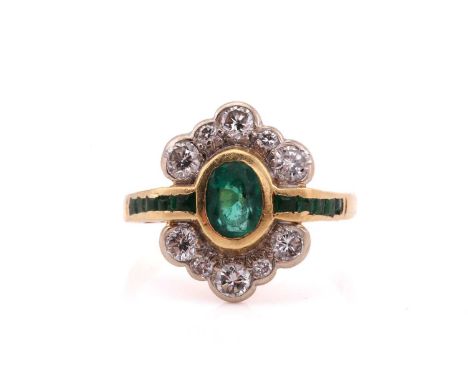 An 18ct bi-coloured gold Art Deco style emerald cluster ring, consisting of an oval emerald at the centre, approximately meas