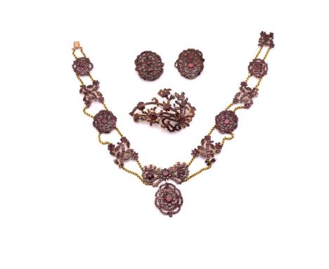 An early 19th century garnet parure, including a long necklace set with alternating floriate design clusters of flat-cut garn