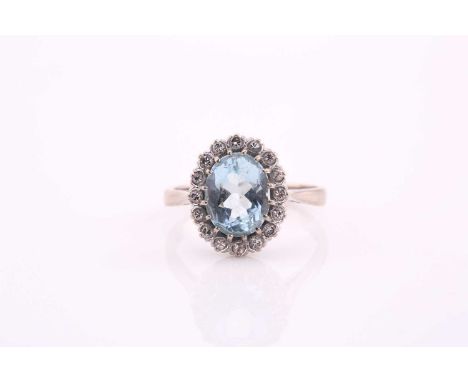 An aquamarine and diamond cluster ring, the oval mixed cut aquamarine 10.2mm x 8mm, surrounded by brilliant cut diamonds, set