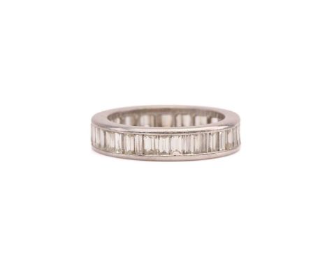 A diamond eternity ring, comprises baguette-cut diamonds of different widths, channel set on a white precious metal mount, un