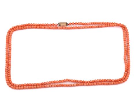 A coral necklace, comprises a string of round pale orangey-pink coral beads of 5 mm, attached with a plain yellow metal box c