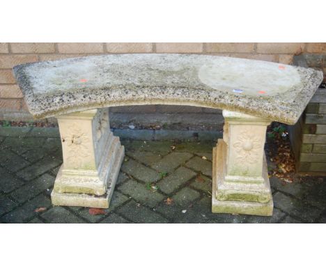 A reconstituted stone curved garden bench raised on end stepped pedestals, width 114cm, together with a reconstituted stone c