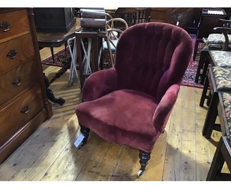 A Victorian walnut framed button back drawing room easy chair in faded plum velvet, on turned tapered supports with brass cap