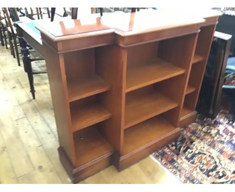 A reproduction yew wood breakfront bookcase, the crossbanded top above a centre open shelf section, flanked by open shelf sid