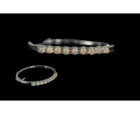 Opal and Natural Zircon Bangle, nine oval cut opals, with a wonderful display of colours, set with sparkling natural zircons,