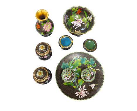 A collection of Chinese cloisonné enamel vessels, some with stands, all worked on a black background in floral designs, plate