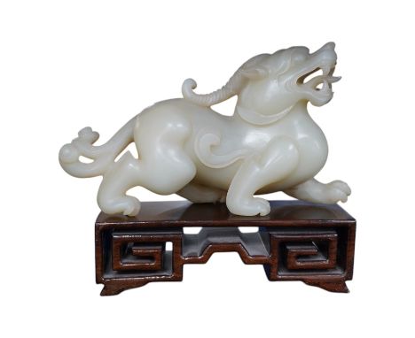 A large Chinese archaistic white jade figure of a mythical beast, hardwood stand, 9cm high, 16cm wide. Condition - good.