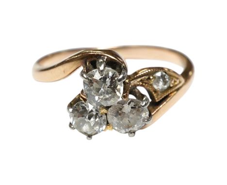 A yellow metal and three stone diamond set crossover ring, with single stone diamond set shoulder, size K, gross weight 2.4 g