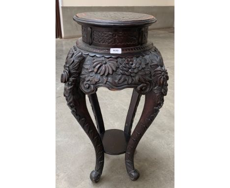 A late 19th century Chinese ebonised pot stand, the top with incised dragon, the carved overall with foliage in high relief. 