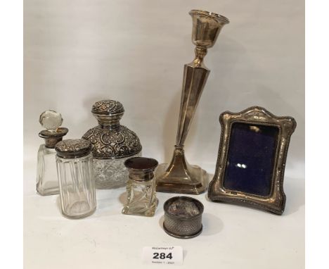 A loaded silver candlestick; a silver photograph frame; a silver napkin ring and three silver topped jars (the globular examp