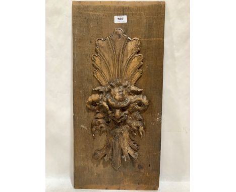 A wood panel carved with a grotesque mask in high relief. 23½' x 11'