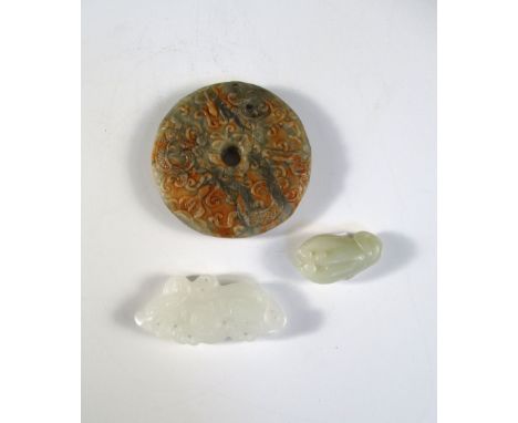 A white jade pendant, another pale green and a bi, the first pierced and carved as a mythical beast, 6cm (2.25 in) wide, the 