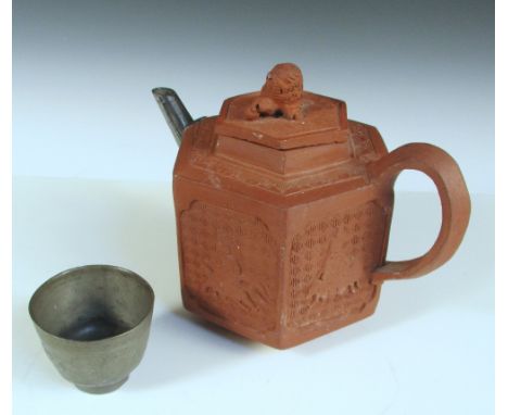 An 18th century Yixing tea pot together with a pewter tea bowl, the hexagonal sides of the pot with horse borne figures in re