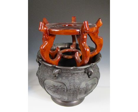 A late 19th/early 20th century bronze planter with wood stand, the petal edged rim above elephant heads in the cavetto formin