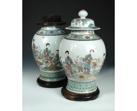 A pair of 19th century famille rose jars, a cover, a wooden cover and two stands, the baluster bodies painted with mirror ima