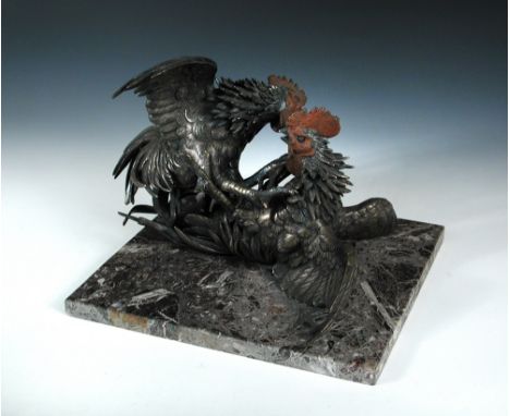 A pair of early 20th century silvered bronze cockerels fighting, one on top of the other as they interlock on the mottled pin