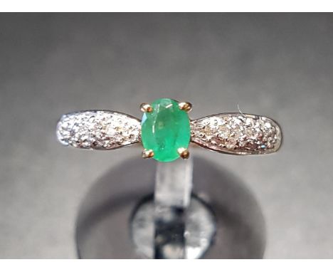 EMERALD AND DIAMOND RINGthe central oval cut emerald flanked by pave set diamond shoulders, on nine carat gold shank, ring si