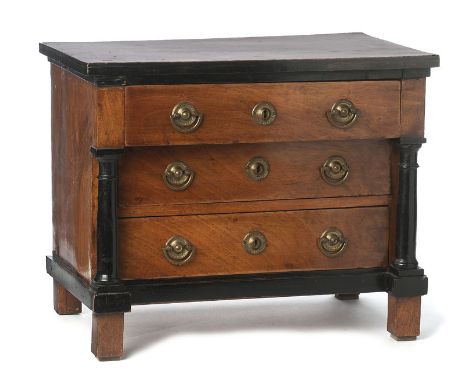 Commode miniature début XIXe en placage de noyer ouvrant par trois tiroirs en façade encadrée par deux colonnes en bois noirc