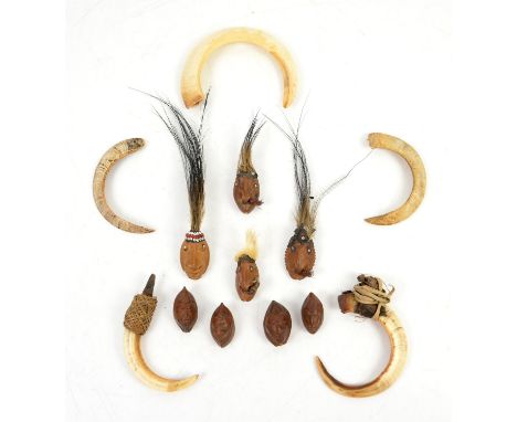 Four amulet masks carved from Galip nuts, Sepik River, Papua New Guinea, three with feather and bead headdresses, one with fi