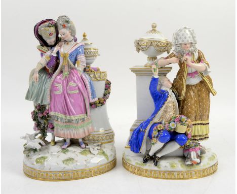 Pair of Dresden figural groups one depicting a gentleman seated with a basket of flowers with a lady standing at his side lea