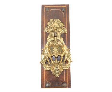Brass door knocker in the form of a beasts head with putti standing on scrolls - 31 cm overall 