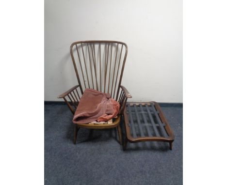 An Ercol elm and beech wingback armchair with stool (no cushions, only covers)
