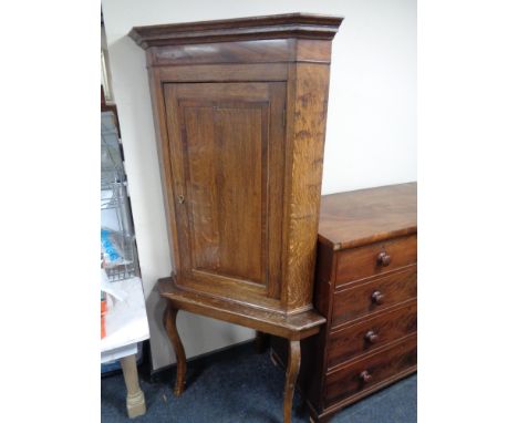 A George III oak corner cabinet on later stand 