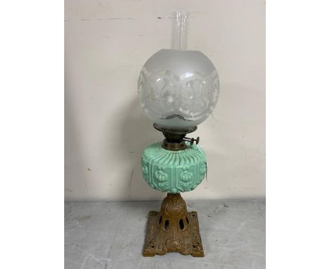A 19th century oil lamp on cast iron base with green glass reservoir, chimney and shade 