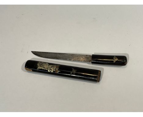 A Japanese miniature sword encased with black lacquered handle and scabbard, set with white metal design of deer beside pagod