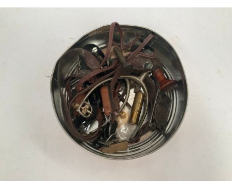 A tin of miscellaneous militaria and collectables including WWII headset, stirrups and a trench art cigarette lighter etc 