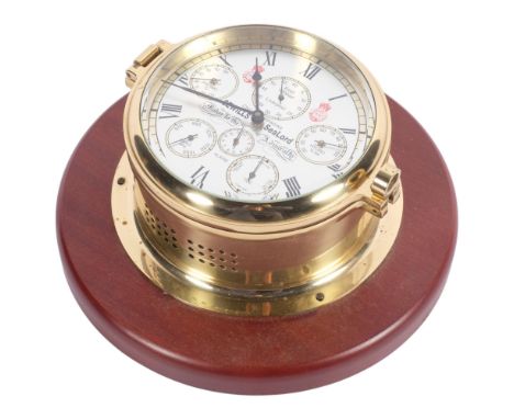 A Sewills SeaLord brass bulkhead clock, with silver dial and brass case, on wooden circular plinth, overall diameter  approx 