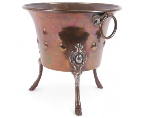 An Arts and Crafts copper jardiniere, having 2 ring handles, decorated with applied circular bosses, raised on 3 hoof feet, w