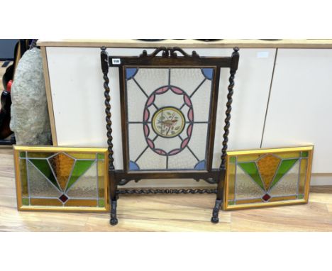 An early 20th century stained glass oak firescreen, height 84cm together with a pair of Art Deco style stained glass panels