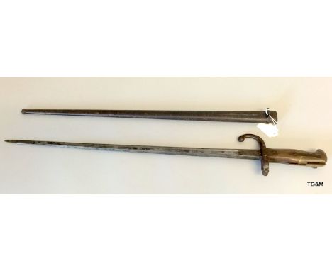 A French model 1874 Gras Sword Bayonet in its steel scabbard. Marked to the reverse of the blade Mre d'Armes de St.Etienne Ma