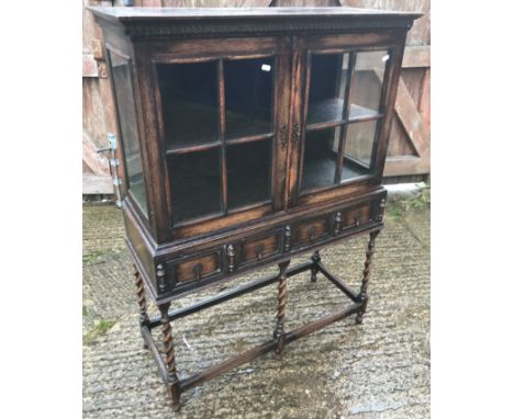 An early 20th Century oak display cabinet in the 17th Century style, the two glazed and barred doors enclosing a single shelf