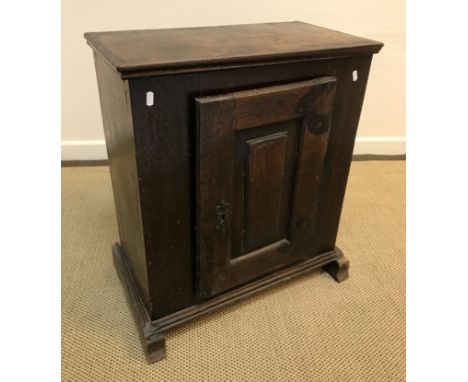 An 18th Century Dutch oak dwarf cupboard, the fielded panelled door enclosing a single shelf, raised on sledge type supports,