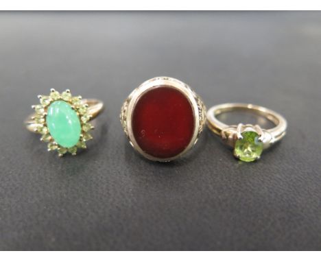 Three 9ct gold rings - To include a peridot single-stone, a green and white-gem cluster - Together with a carnelian signet ri