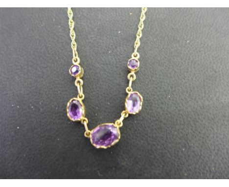 A 9ct gold oval amethyst necklace - The graduated collets to the fancy-link chain - Hallmarked London - Length 39cms - Weight